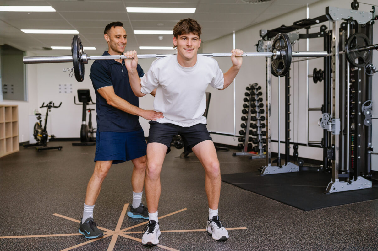 West LakesPhysio assisting squat technique in Rehab Gym